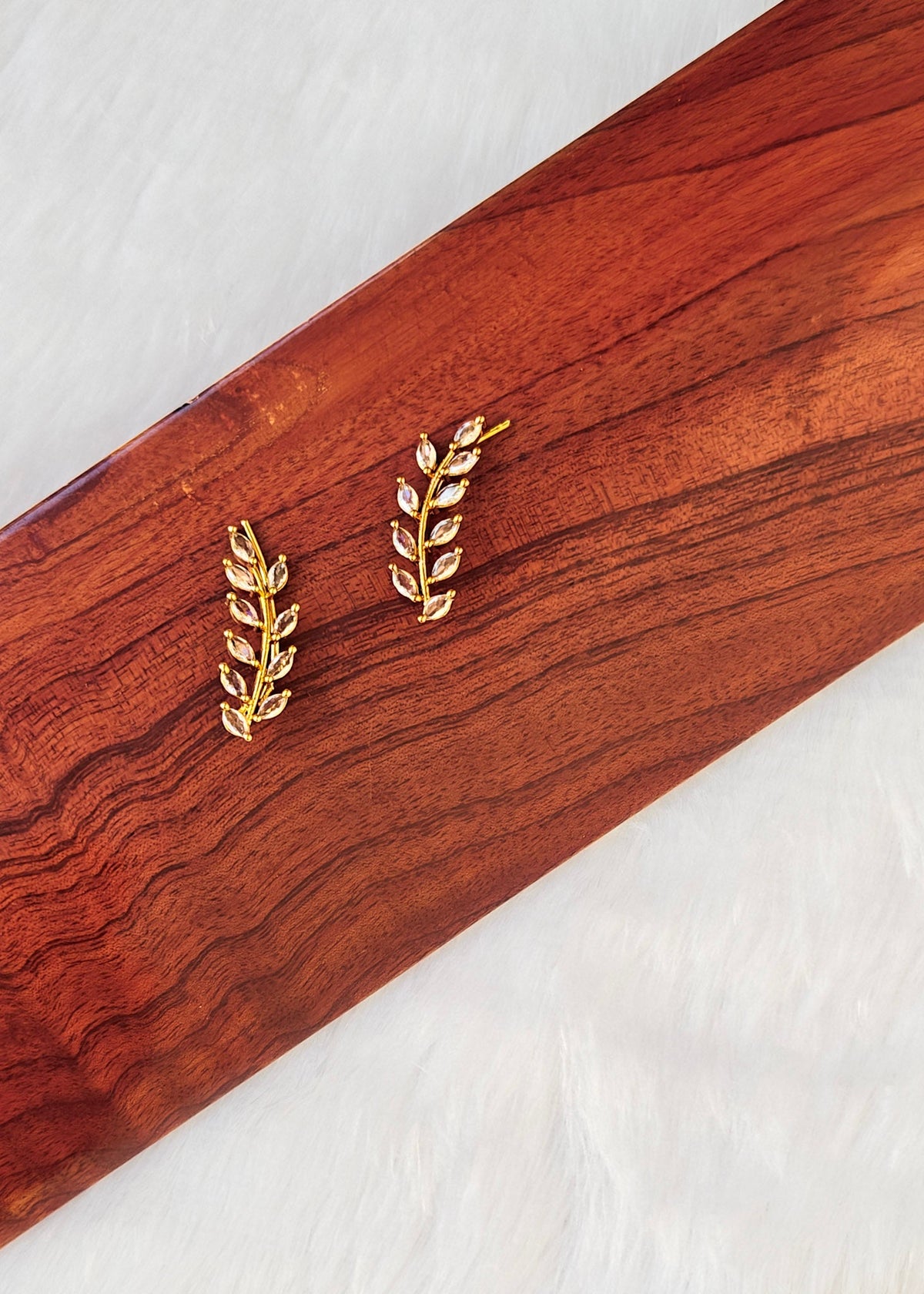A pair of gold leaf-shaped stud earrings.