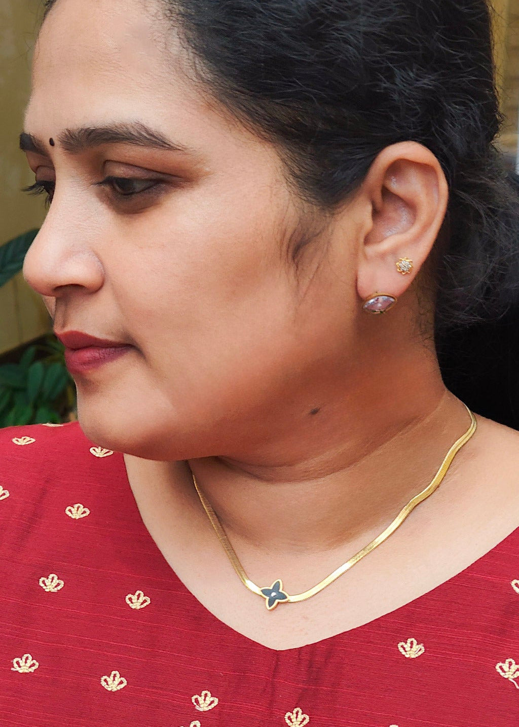 A close-up side profile of a woman wearing an anti-tarnish gold necklace,