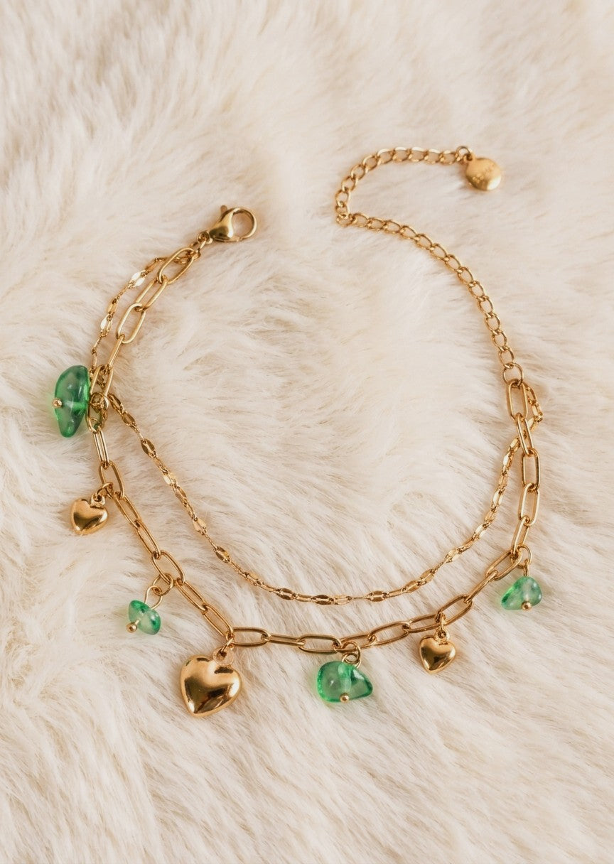 Anti tarnish gold bracelet with golden heart and green stone charms.
