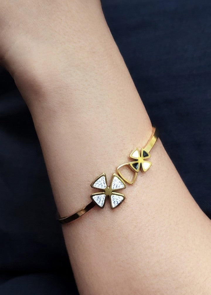A gold-plated cuff bracelet with three butterfly charms, two of which are decorated with small clear crystals, shown worn on a person's wrist.