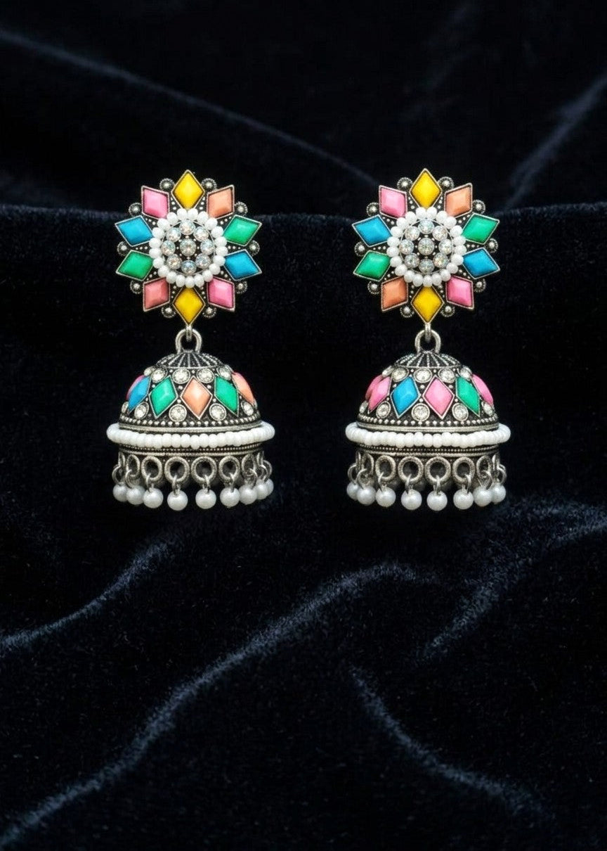 A pair of traditional Indian jhumka earrings with silver-toned metalwork and vibrant multicolor enamel details, displayed on a black velvet background.