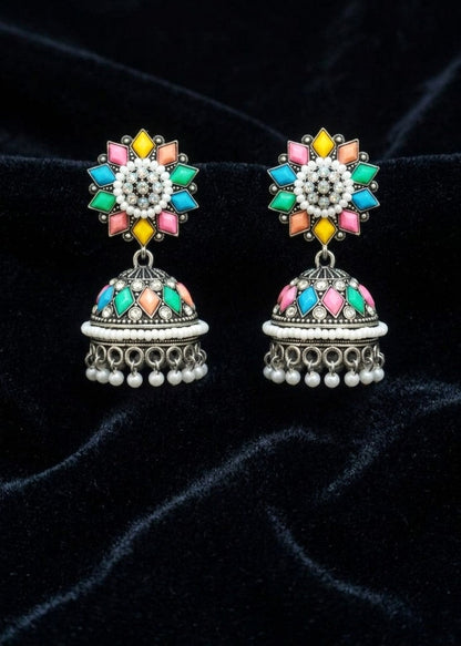 A pair of traditional Indian jhumka earrings with silver-toned metalwork and vibrant multicolor enamel details, displayed on a black velvet background.