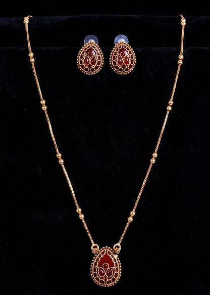 Gold-toned jewelry set featuring a beaded necklace with a teardrop pendant and matching stud earrings, decorated with red enamel and white floral detailing, displayed on a black velvet background.