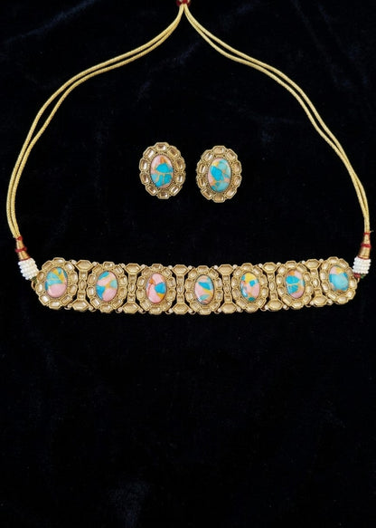 Gold-plated traditional Indian jewelry set featuring a choker necklace with seven oval opal inlays and matching stud earrings, displayed on a black velvet background.