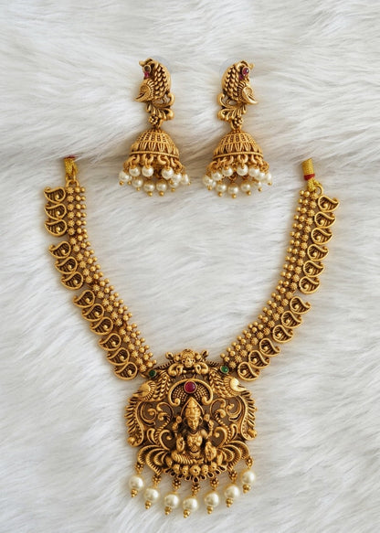 Gold-toned traditional Indian jewelry set featuring a necklace with a detailed Lakshmi pendant, matching earrings, and pearl accents, arranged on a white faux fur background.