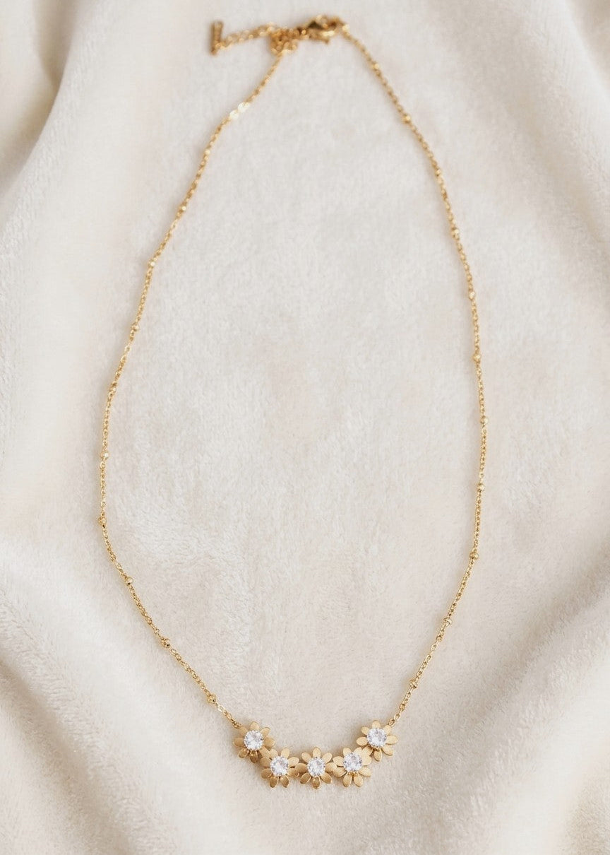 Jenny floral rhinestone necklace laid on cream fabric, showing the gold-toned beaded chain and extension clasp.