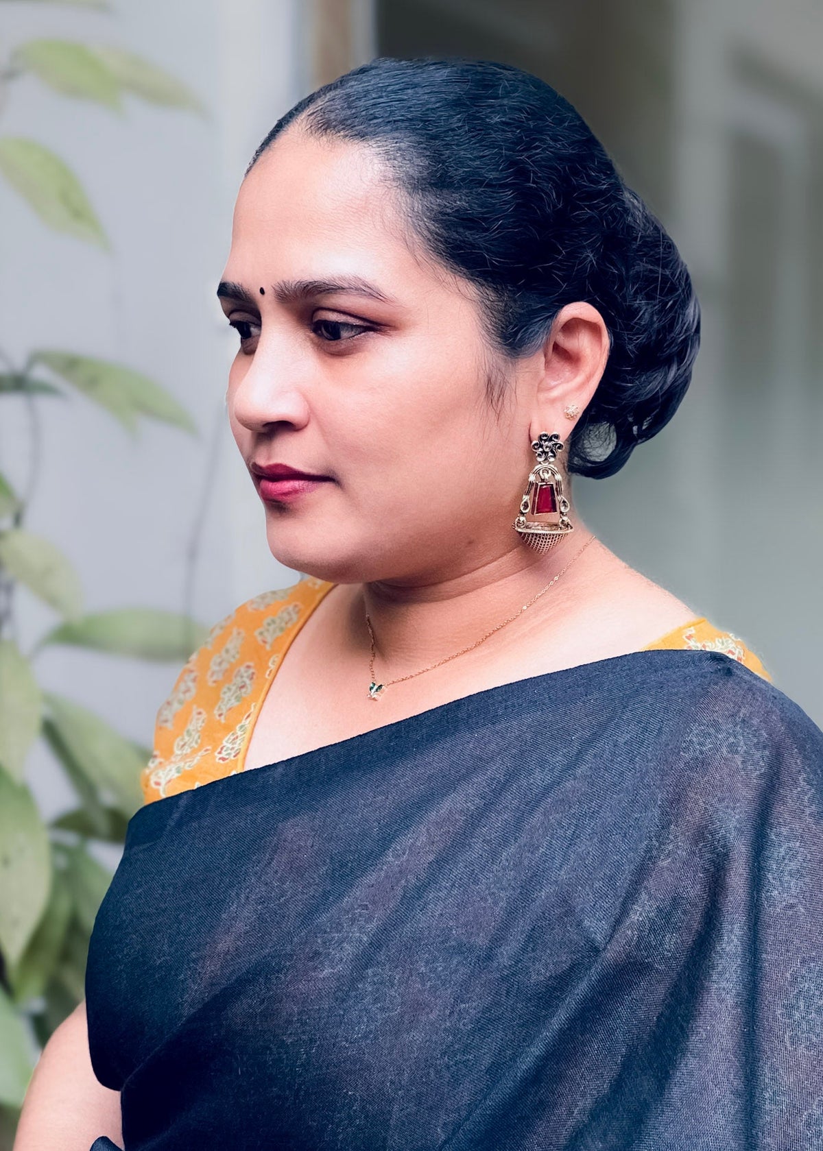 A woman wearing a red-and-gold earrings, 