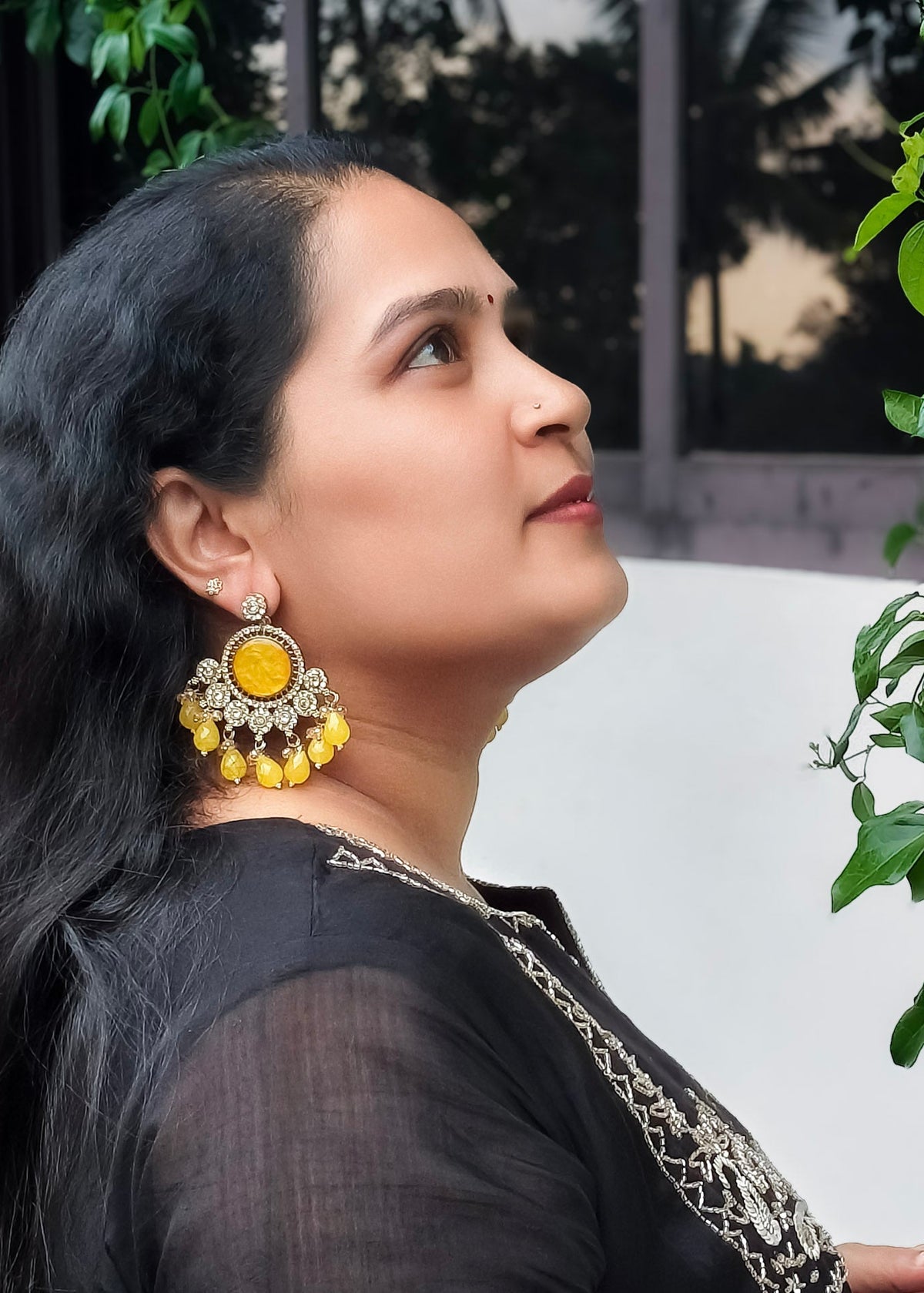 A woman wearing large yellow and gold statement earrings