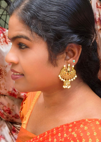 A woman in profile wearing a large ornate gold jhumka earring with white bead drops