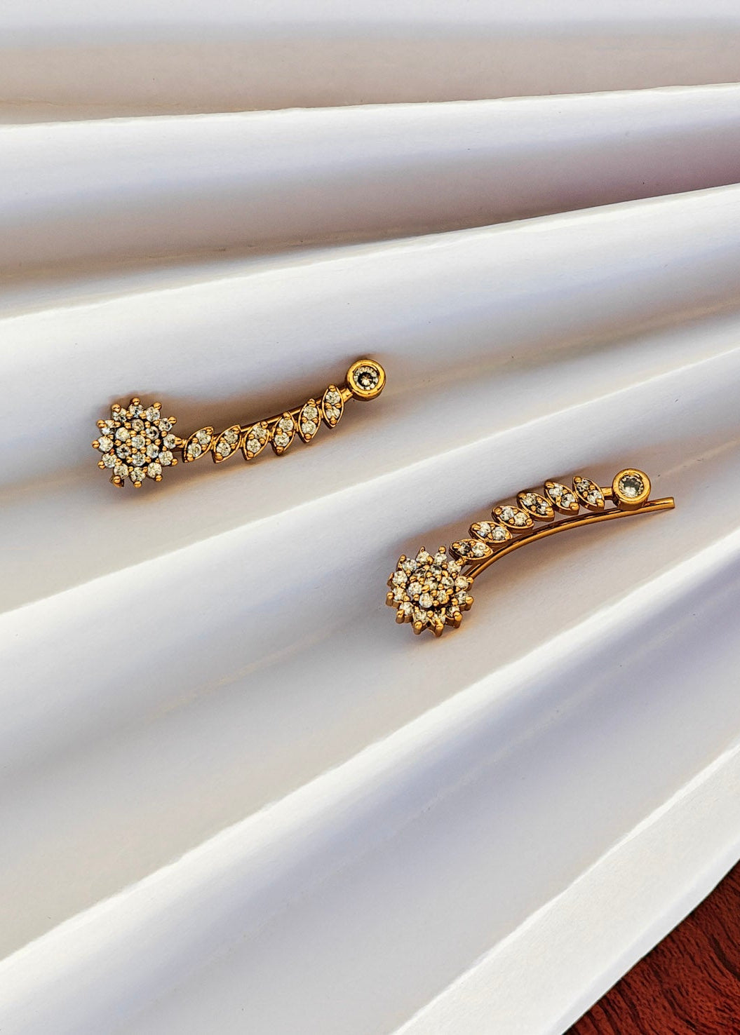 A pair of gold-toned curved hair clips decorated with small clear crystals.