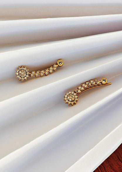 A pair of gold-toned curved hair clips decorated with small clear crystals.