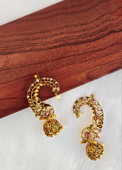 A pair of ornate gold-toned traditional earrings with red, green, and pink stone embellishments.