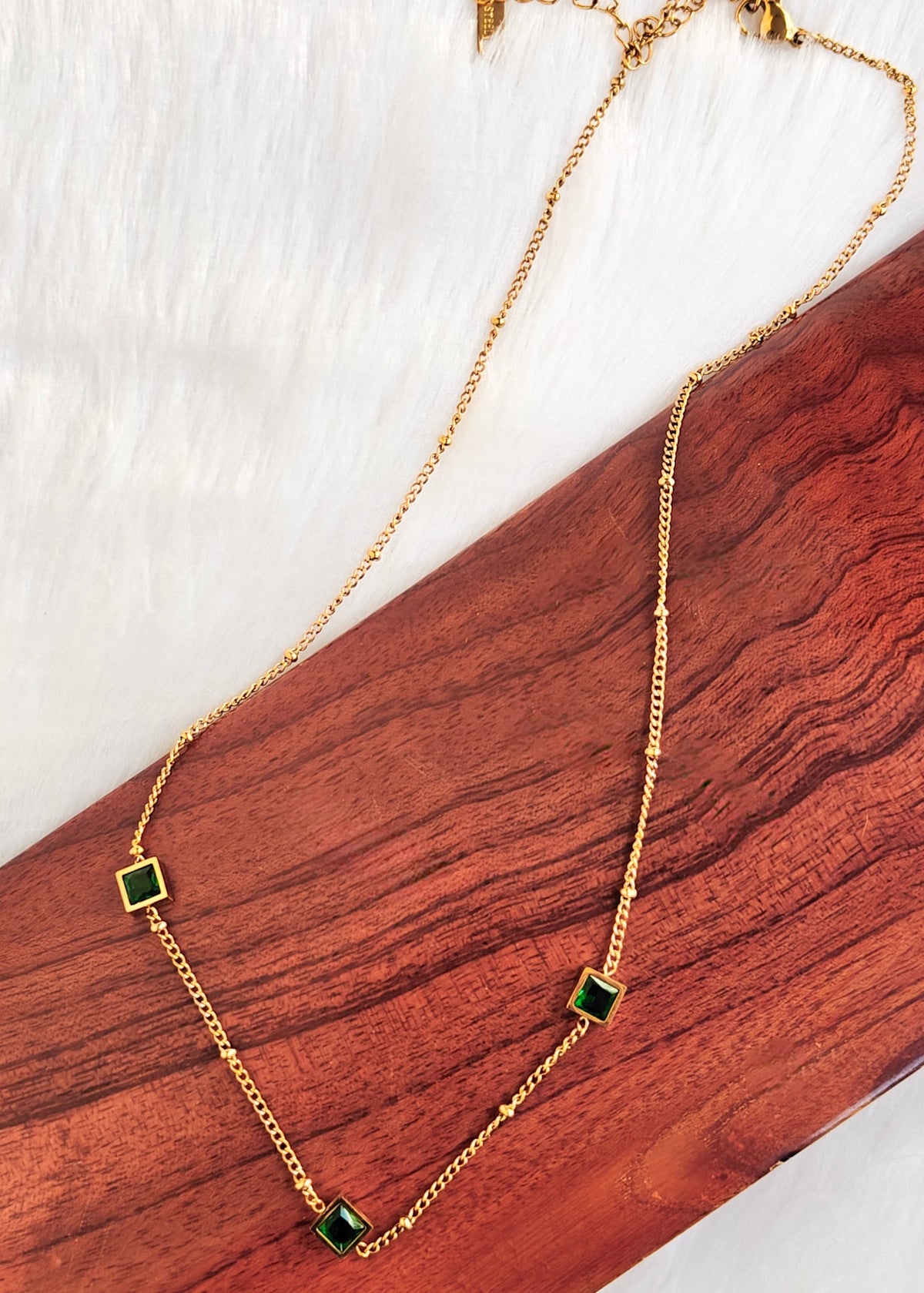 An anti-tarnish gold chain necklace with four small square green stone accents