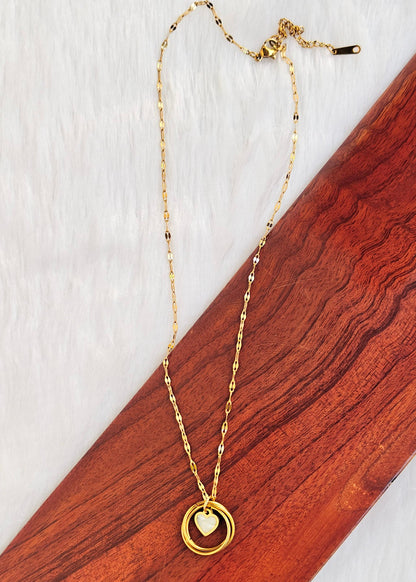 Afreen gold-toned necklace with interlocked ring pendant and a white heart-shaped centre, shown on a white and wooden background.