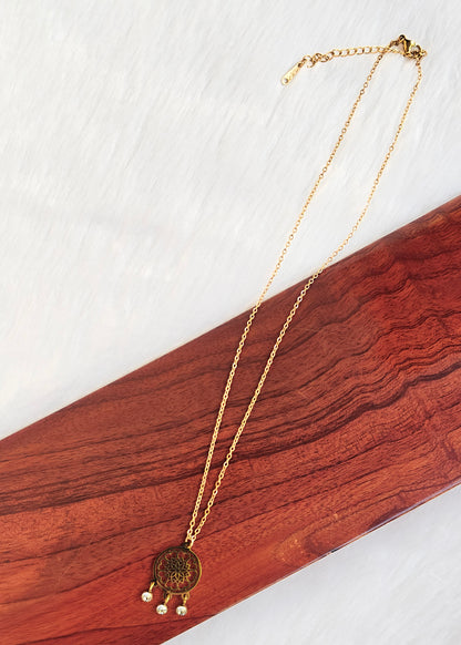 A gold-toned chain necklace with a round medallion pendant and three small dangling pearl-like beads, 