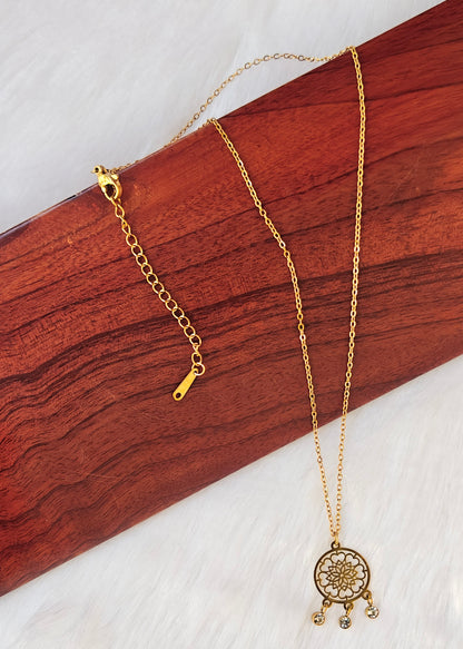 A gold-toned necklace with a circular mandala pendant and small dangling charms,