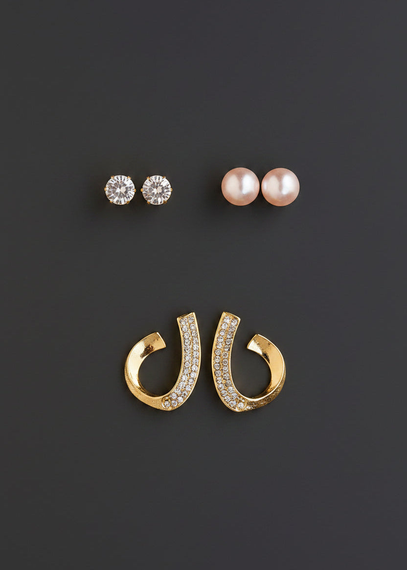 Three pairs of stud earrings; two pairs with clear round stones and one pair with white pearl-like beads, plus a pair of gold hoop earrings with clear stones, 