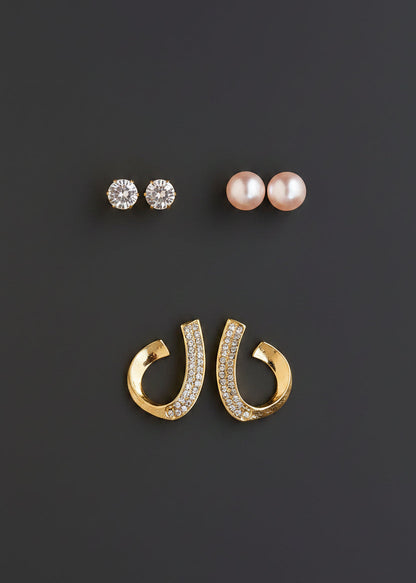 Three pairs of stud earrings; two pairs with clear round stones and one pair with white pearl-like beads, plus a pair of gold hoop earrings with clear stones, 