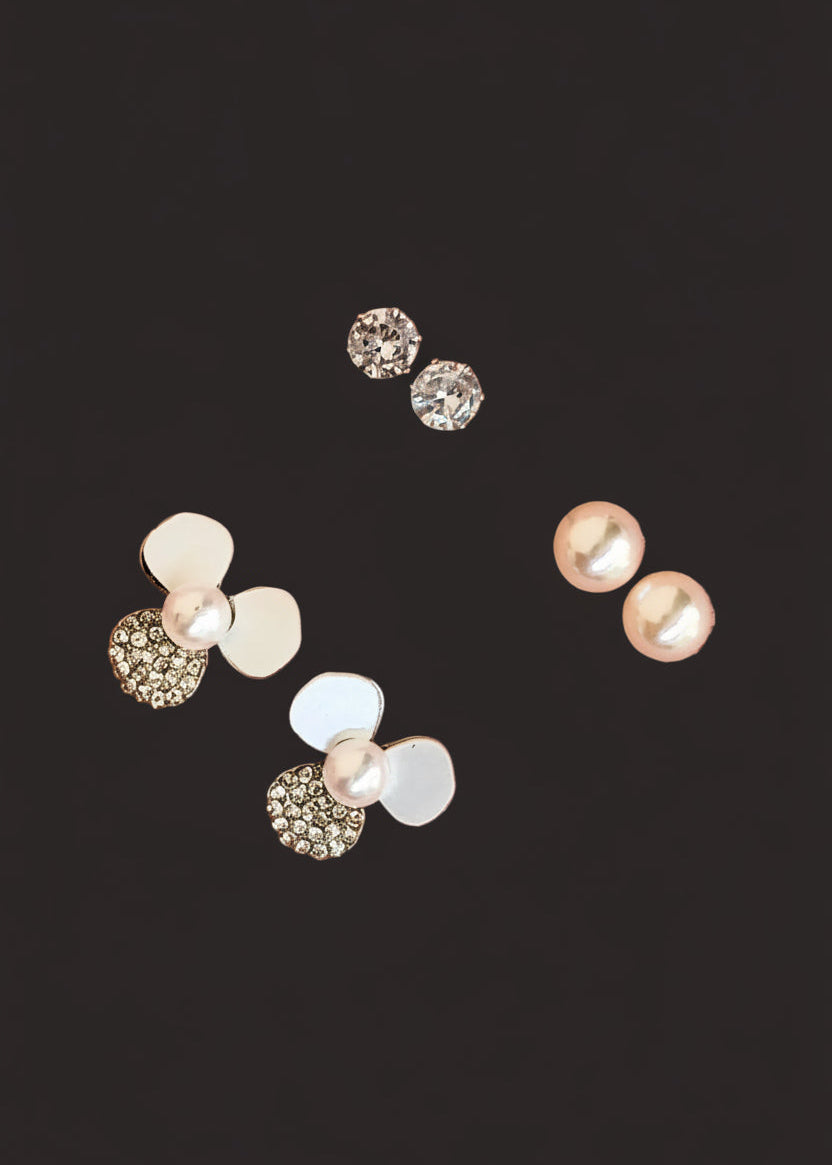Three pairs of stud earrings. The earrings feature white faux pearls, clear rhinestone-covered round studs, and a cluster design combining white discs, clear rhinestones, and a pearl.