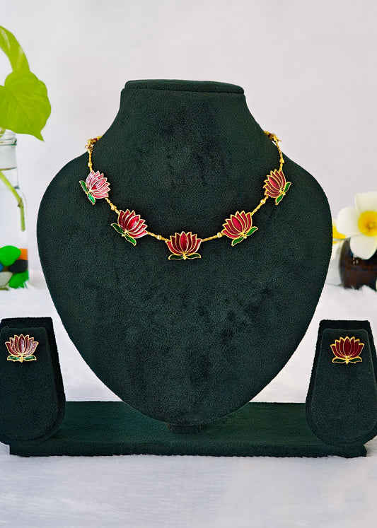 Gold-tone lotus flower jewelry set displayed on a black velvet mannequin bust, including a necklace, matching earrings, and a small stand, with decorative flowers in the background.