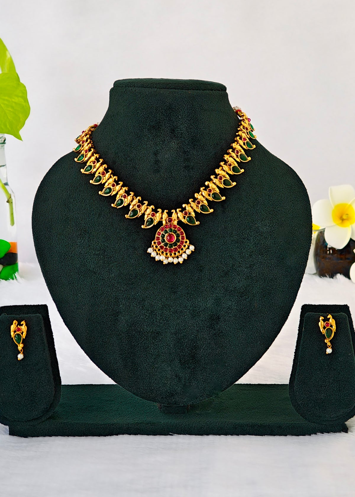 Gold-toned traditional necklace and matching earrings displayed on a black velvet jewelry bust against a white background.