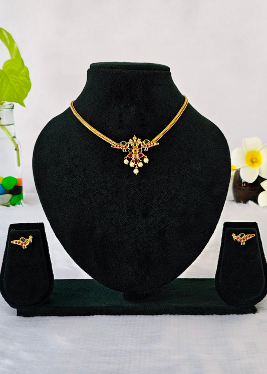 Gold jewelry set displayed on a black velvet mannequin bust, including a necklace with a floral pendant, a matching stud earring, 