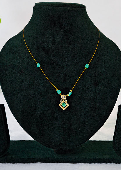 A gold necklace with turquoise-colored beads and a geometric pendant, displayed on a black velvet jewelry bust.