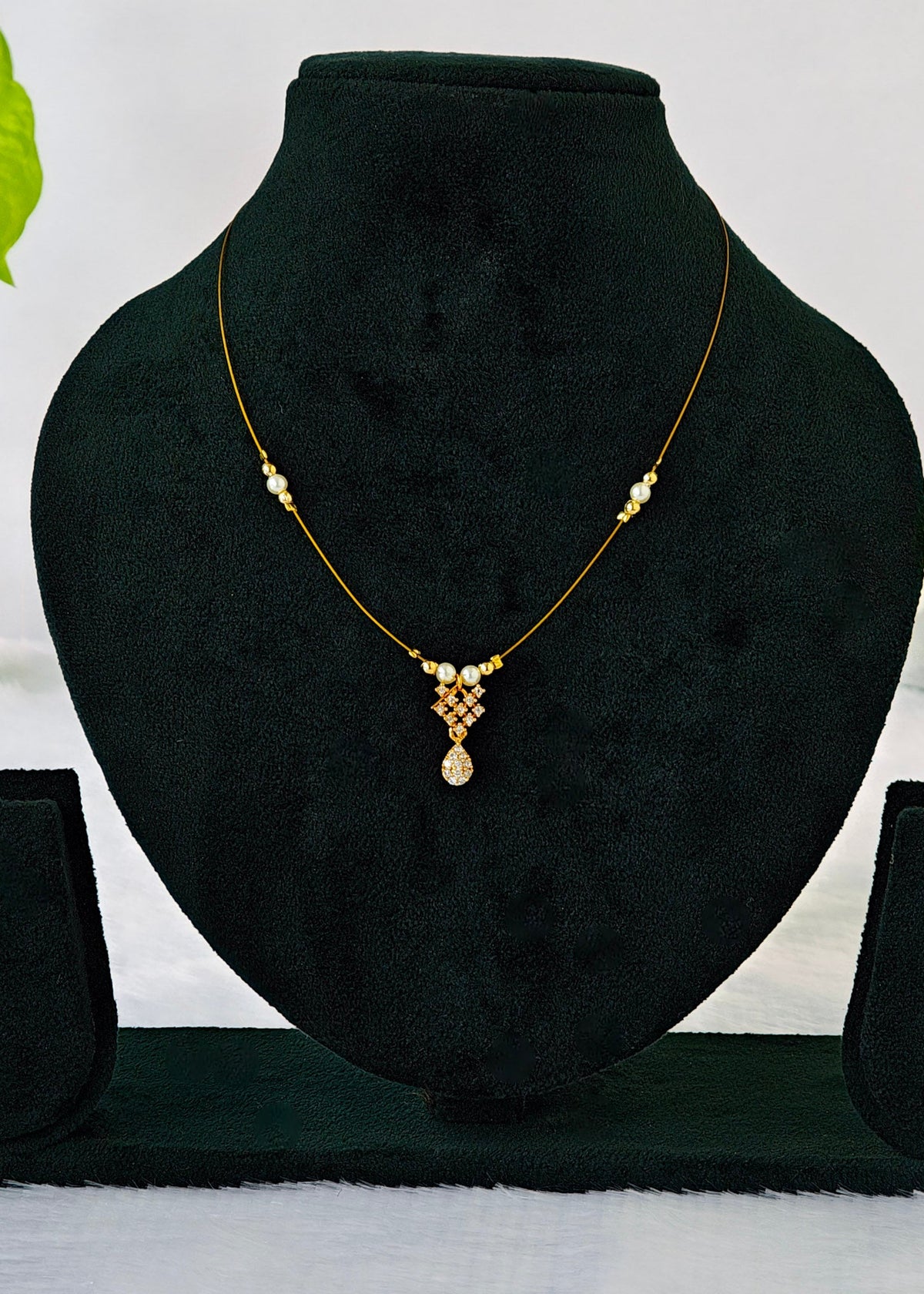 Haya fine-wire necklace with white pearl accents, a crystal lattice and teardrop charm on a black display