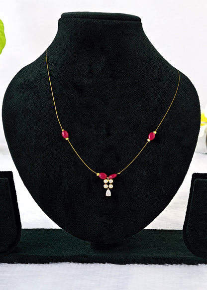 Kashish fine-wire necklace with ruby-red oval beads, a white crystal cluster and teardrop pendant on a black display.
