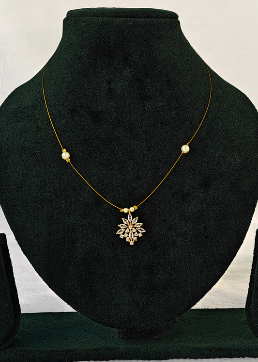 A delicate gold necklace with a central gold snowflake pendant and small gold beads, displayed on a black velvet jewelry bust.