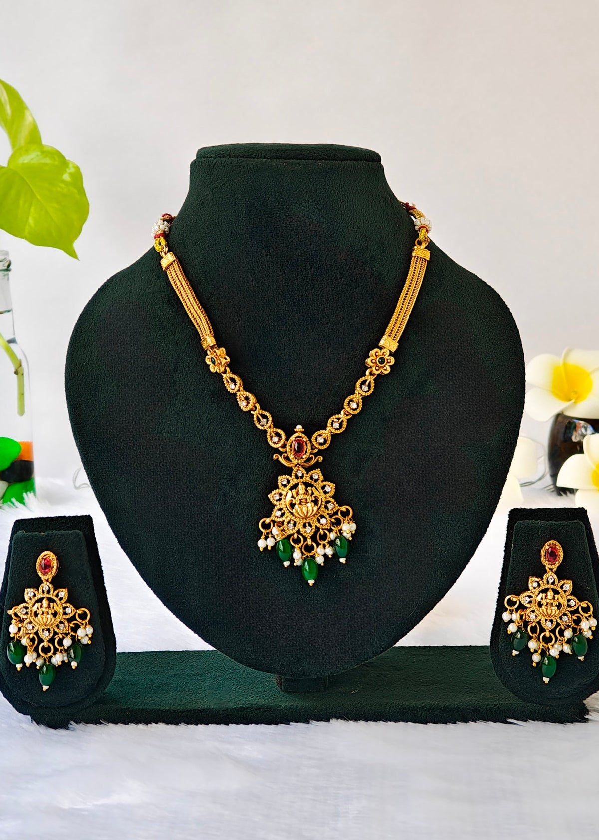 Vidya gold-plated Lakshmi temple necklace and matching earrings with red stones, green drops and pearl clusters.