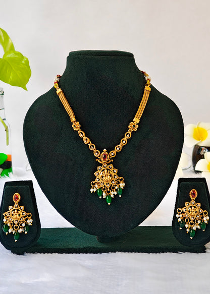 Vidya gold-plated Lakshmi temple necklace and matching earrings with red stones, green drops and pearl clusters.