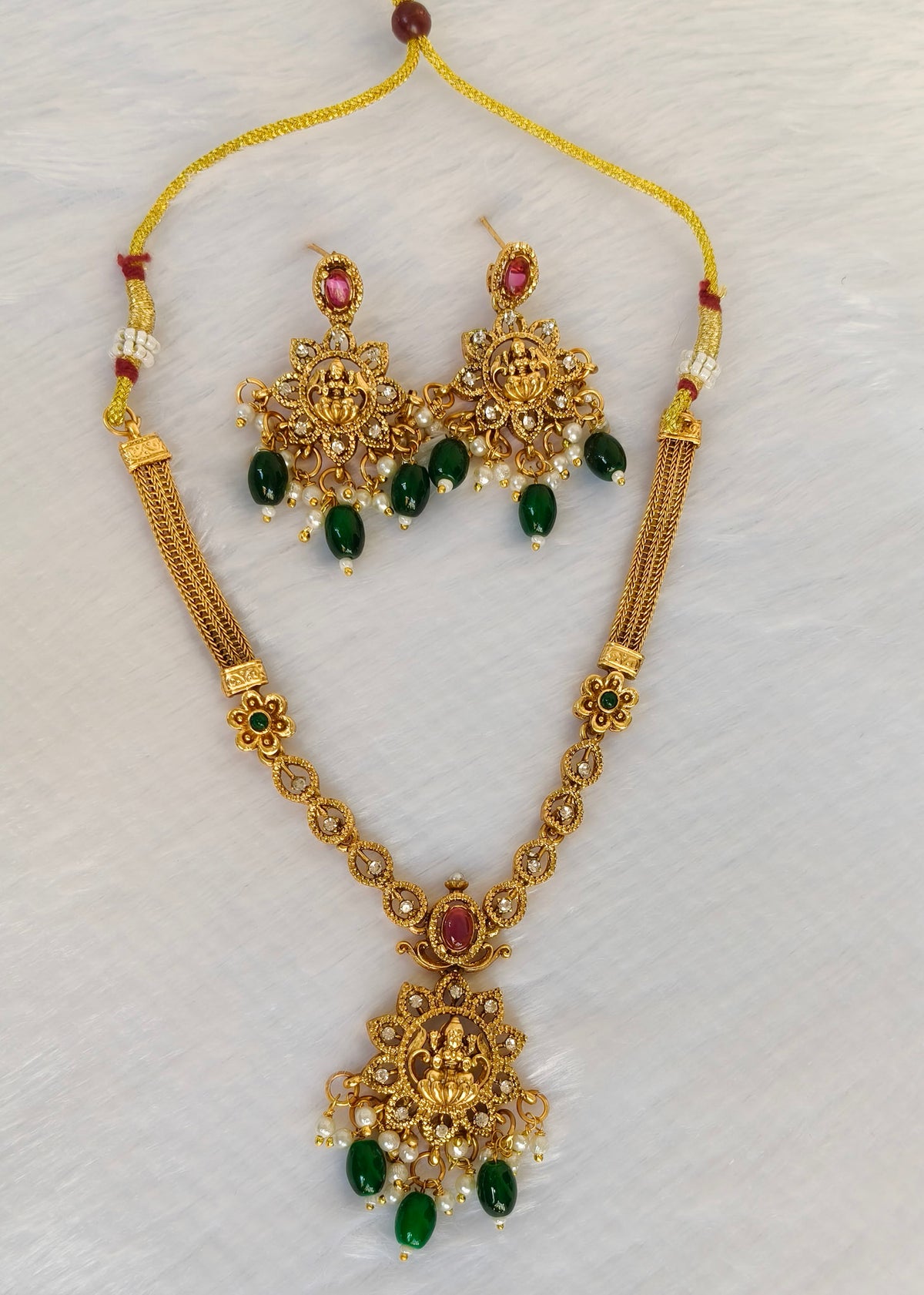 Vidya gold-plated Lakshmi temple necklace and matching earrings with red stones, green drops and pearl clusters.