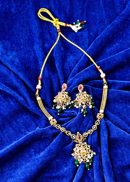 Vidya temple necklace and earrings on blue fabric, with Lakshmi motifs, red stones, green drops and pearl clusters.