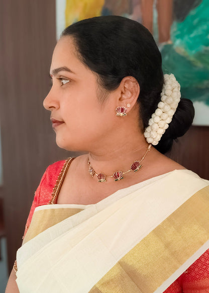 A woman in profile wearing a lotus motif gold necklace and earring