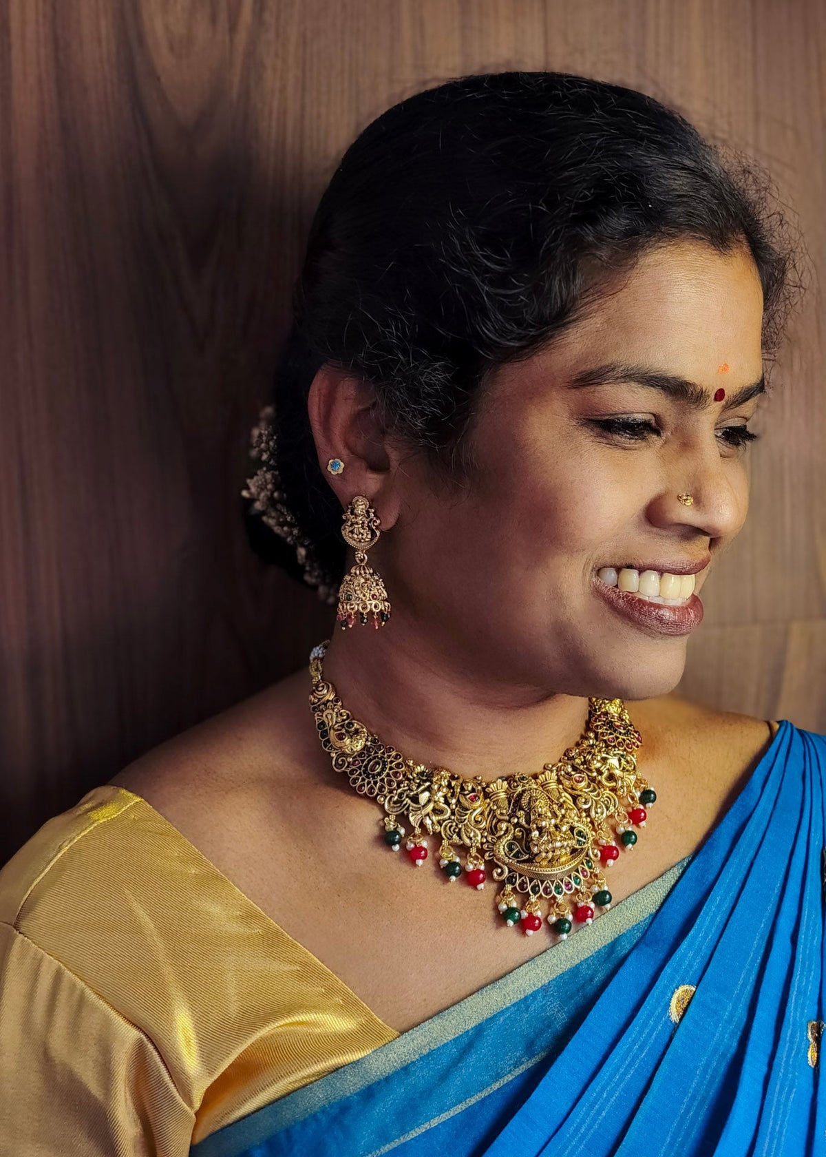 A woman wearing an ornate gold-toned traditional necklace and matching earrings
