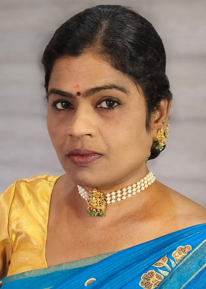 A woman wearing a bright blue saree with gold floral embroidery and a gold blouse, accessorized with a pearl necklace and gold earrings.