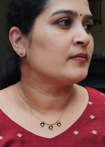 Aashiya triple black heart crystal necklace worn with a red embroidered top, showing how the charms sit at the neckline.