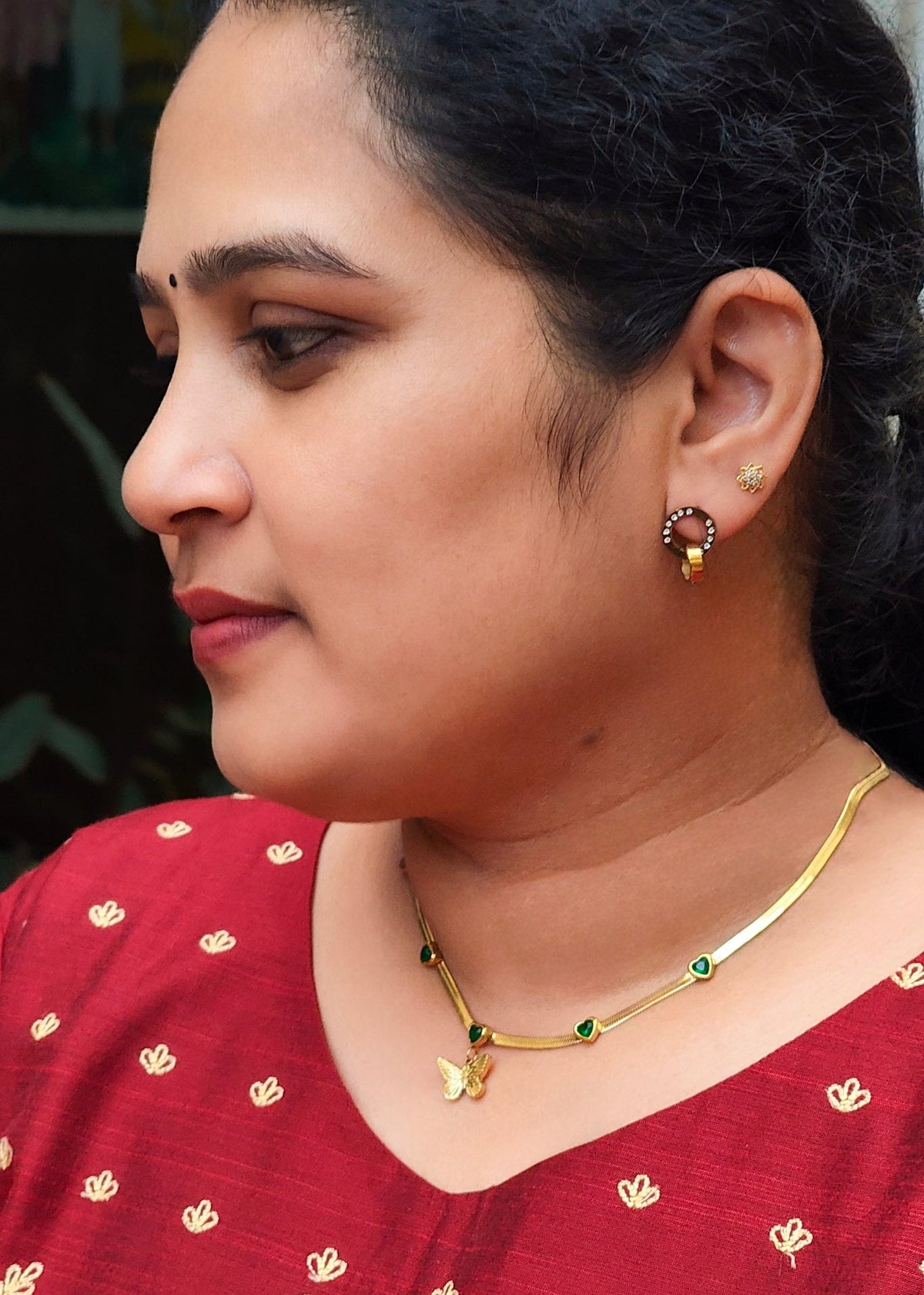 A close-up side profile of a woman wearing anti tarnish gold necklace with a butterfly pendant 