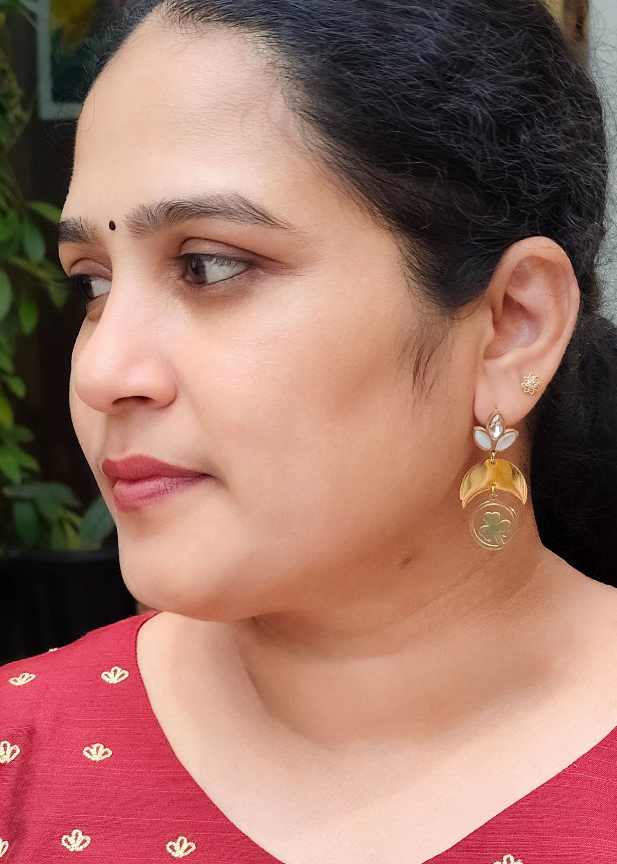 A close-up side profile of a woman wearing an anti-tarnish crescent moon gold plated and white dangle earring.