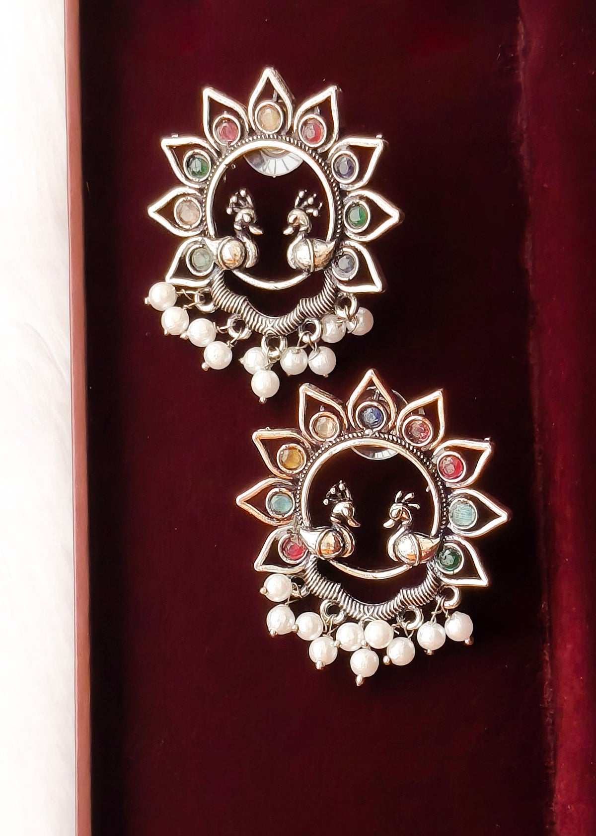 Silver toned sunflower multi color stone adorned earring with peacock motif pattern.