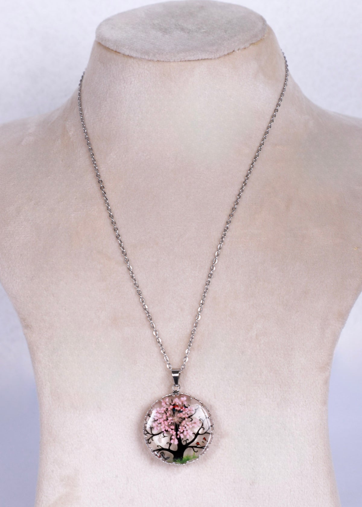 Anti tarnish silver chain necklace with a round pendant featuring a cherry blossom tree design, displayed on a beige fabric mannequin bust.