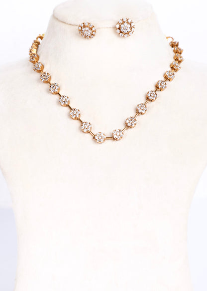 A gold-tone jewelry set displayed on a cream-colored mannequin bust, featuring a floral cluster necklace and matching stud earrings.