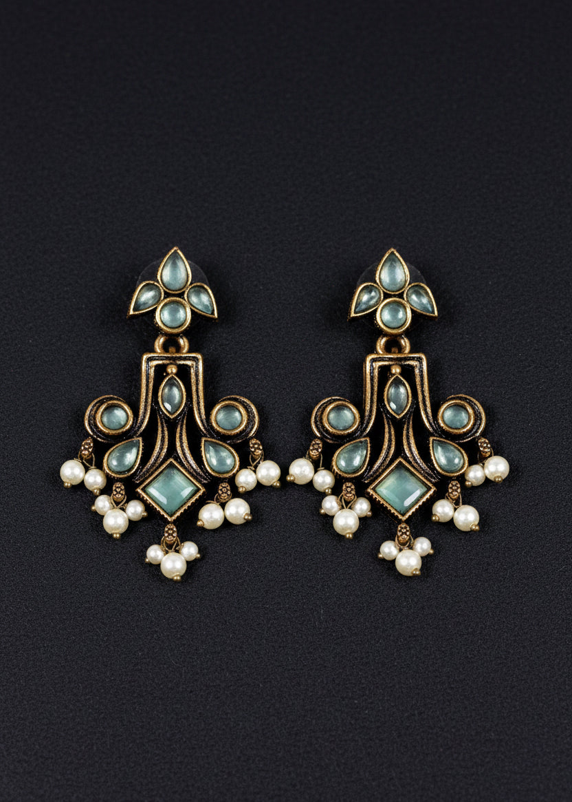 A pair of ornate dangling earrings. The earrings feature antique bronze-toned metalwork with pale blue-green stones and small white pearl drops.