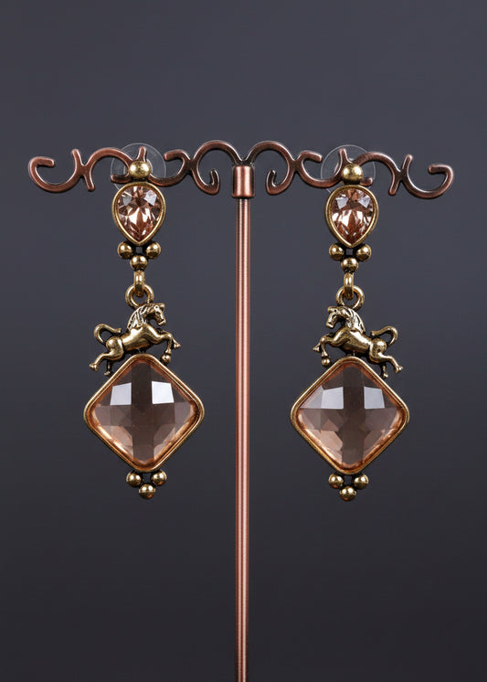 A pair of antique-style drop earrings. The earrings feature oval rose-gold-toned bezel-set stones, small horse charms, and large diamond-shaped pale pink faceted beads.