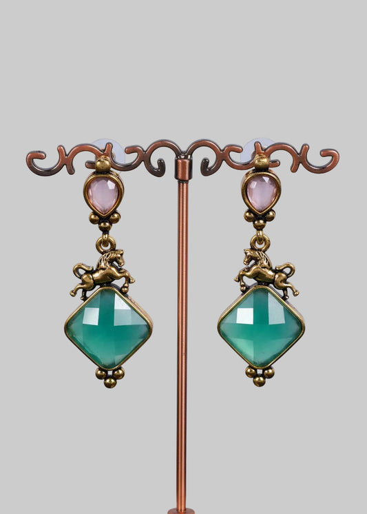 A pair of antique-style drop earrings. Each earring features a faceted light green diamond-shaped gemstone, an antique bronze horse figure, a small oval pale pink stone, and a matching horse connector.