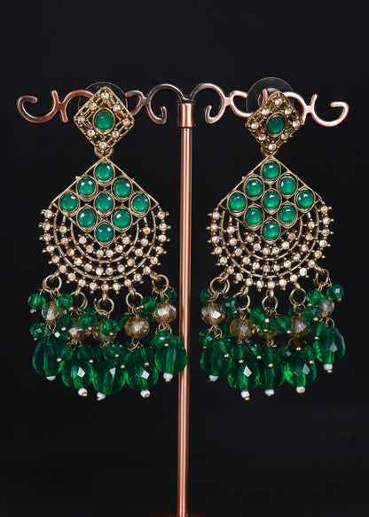 A pair of ornate gold-toned statement earrings with multiple rows of green stones and dangling green bead clusters.