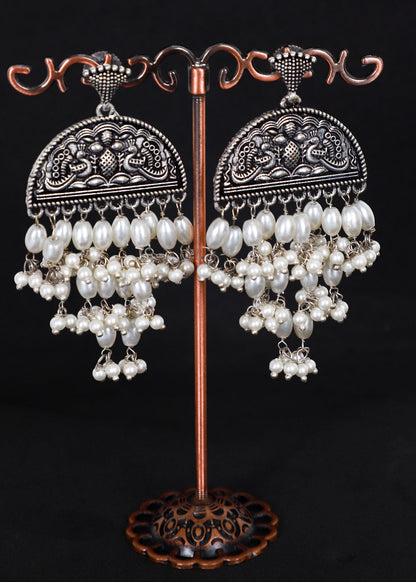 A pair of ornate silver-toned jhumka earrings with white pearl bead cascades.