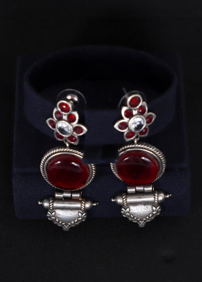 A pair of silver-toned dangle earrings with red gemstone accents.