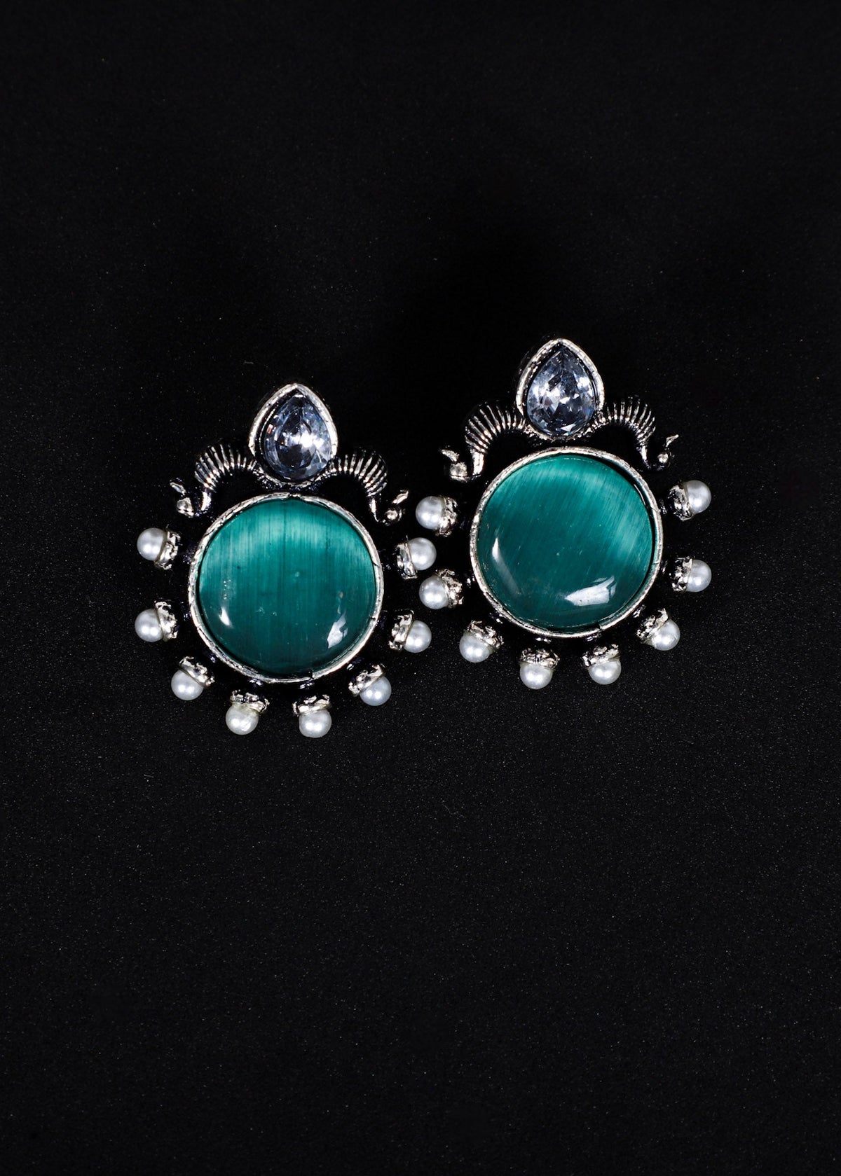 A pair of silver-toned stud earrings featuring oval green cat's eye stones, surrounded by small clear rhinestones and a teardrop-shaped clear stone at the top